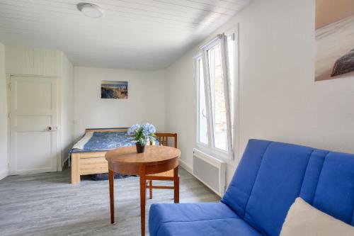 Habitación con cama, mesa y sofá azul en Escale a deux pas de la plage du Val Andre, en Pléneuf-Val-André