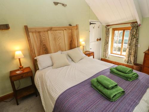 a bedroom with a bed with two green towels on it at Penyrallt Fach Cottage in Llandysul