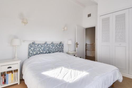 ein weißes Schlafzimmer mit einem großen Bett mit einem blauen Kopfteil in der Unterkunft Escapade familiale a deux pas de la plage in La Guérinière
