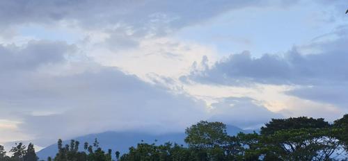 a cloudy sky with trees in the foreground at 1Q rural in Sukabumi