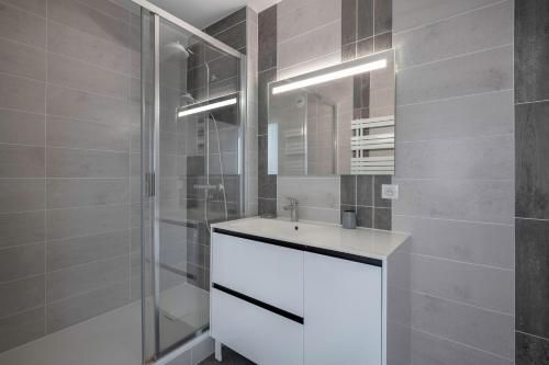 une salle de bain avec un lavabo blanc et une douche dans l'établissement Le Pouliguen - 100 du port - Escale à deux, au Pouliguen