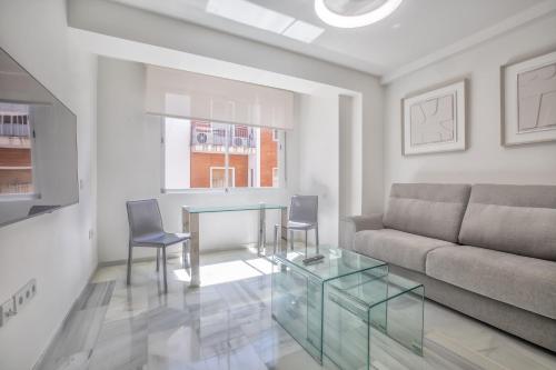 Una sala de estar con una mesa de cristal y un sofá. en Apartamentos Haranas II & Parking, en Córdoba
