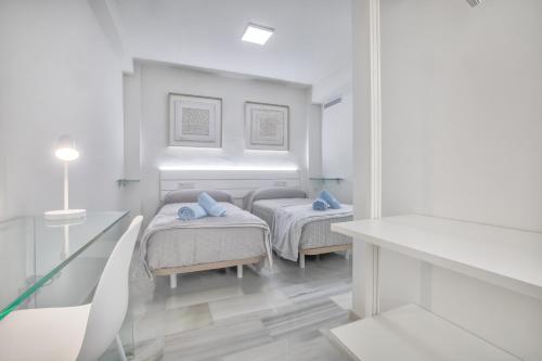Dos camas en una habitación con paredes blancas. en Apartamentos Haranas II & Parking, en Córdoba