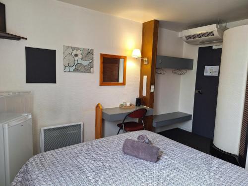 a room with a bed and a desk and a table at Escale Kennedy in Mérignac