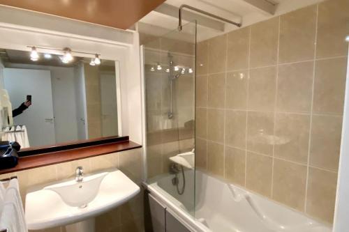 La salle de bains est pourvue d'un lavabo, d'une douche et d'un miroir. dans l'établissement Magnifique appartement plein sud - Piscine, au Croisic