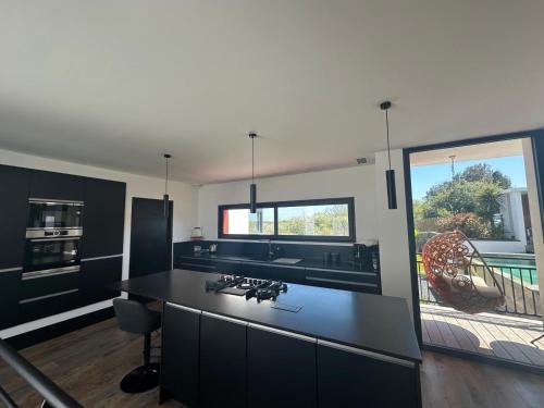 eine Küche mit einer schwarzen Arbeitsplatte und einem großen Fenster in der Unterkunft LA PALMERAIE in Châtelaillon-Plage