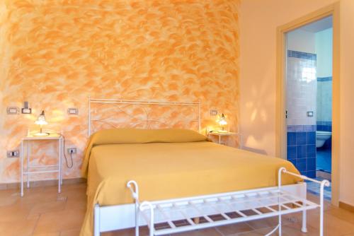 een slaapkamer met een bed en een gele muur bij Hotel Villa delle Palme in Sapri