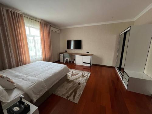 a bedroom with a bed and a desk with a tv at HOTEL DEHLAVI o in Dushanbe