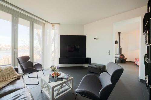 ein Wohnzimmer mit einem Sofa, Stühlen und einem TV in der Unterkunft urlaubsART - Ostsee - Urlaub in Kappelns "Schleibrücke" in Kappeln