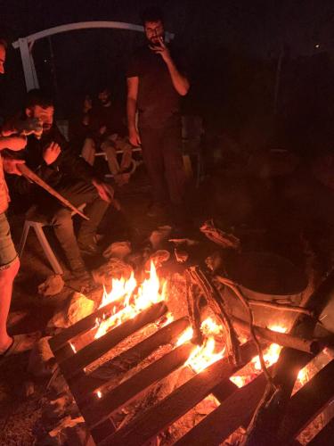 a group of people standing around a fire at BH מתחם קמפינג ואוהלים in Nevatim