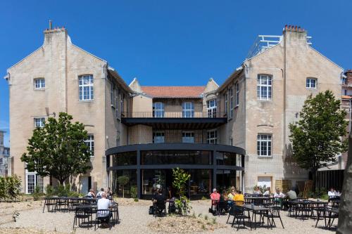 a large building with tables and people sitting in front of it at Hôtel Lilybloom in Le Havre