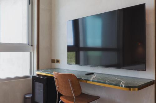 a large flat screen tv on a wall with a chair at PAPO'A Harbor Hotel in Kaohsiung