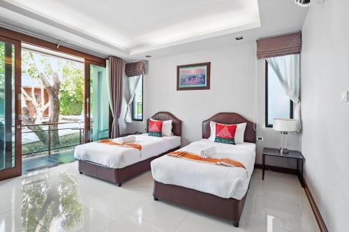 a bedroom with two beds and a balcony at Nutchana Hill Boutique Hotel in Hat Yai