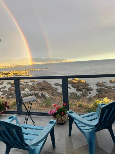 einen Regenbogen über dem Meer mit zwei Stühlen und einem Tisch in der Unterkunft Pacific Ocean House seafront 3bd2bh near airport in Wellington