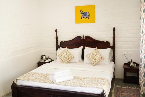 a bedroom with a bed with white sheets and pillows at Heli Pushkar in Pushkar