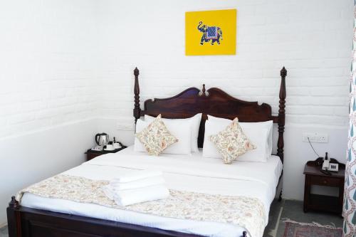 a bedroom with a bed with white sheets and pillows at Heli Pushkar in Pushkar