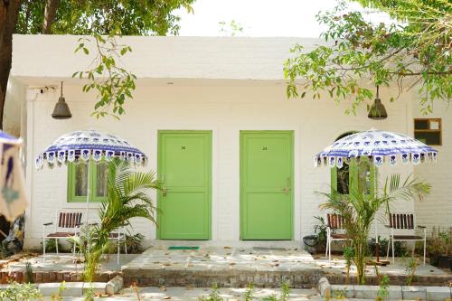 two green doors on a white house with two chairs at Heli Pushkar in Pushkar