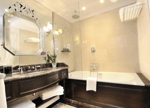 a bathroom with a tub and a sink and a mirror at Auberge du Jeu de Paume in Chantilly