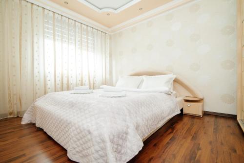 a bedroom with a bed with white sheets and a window at ERA RENT Apartments in Chişinău