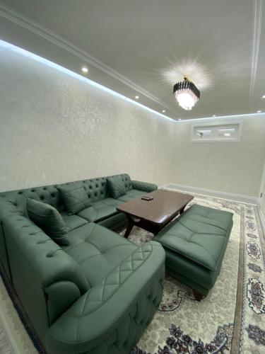 Apartment في سمرقند: غرفة معيشة مع أريكة خضراء وطاولة