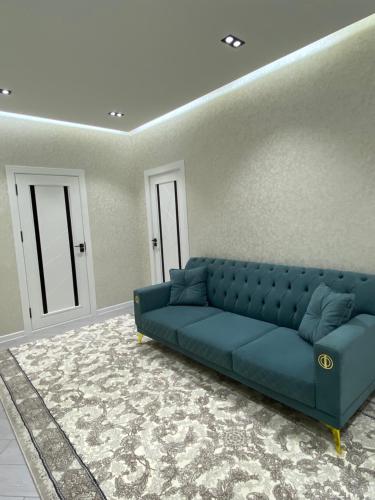 Apartment في سمرقند: أريكة زرقاء موجودة في غرفة المعيشة