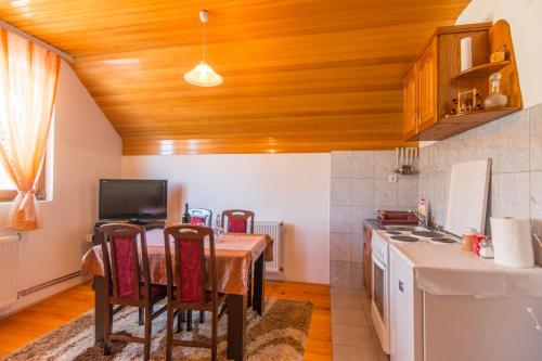 a kitchen with a wooden ceiling and a table with chairs at Kod Goluba na Tari in Šljivovica