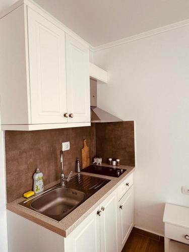 a kitchen with a sink and white cabinets at Orfeu apartments Ksamil in Ksamil
