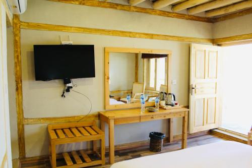 a bedroom with a desk and a television on the wall at Guzel Hotel in Shigar