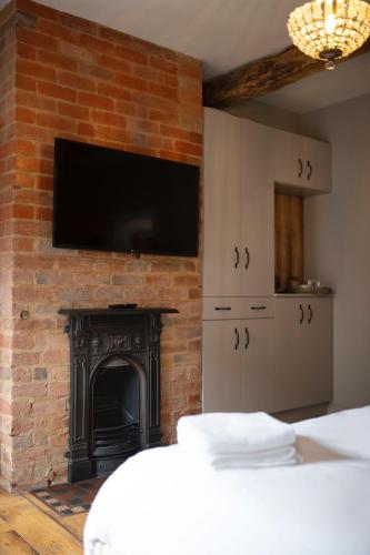 um quarto com uma lareira e uma televisão numa parede de tijolos em Bulls Head Inn Rooms em Alton
