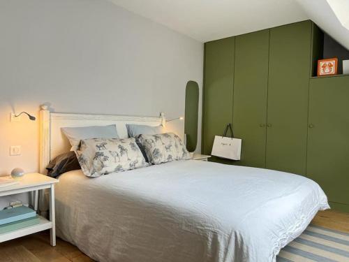 une chambre avec un lit blanc avec un mur vert dans l'établissement Appt standing Coeur de ville Chateau et Marché, à Versailles