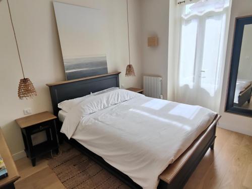 une chambre avec un grand lit blanc et une fenêtre dans l'établissement Pied à terre en bord de mer, à Pornic