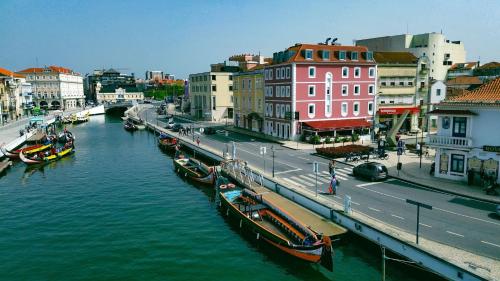 a river with boats in a city with buildings at Maraveiro House in Aveiro