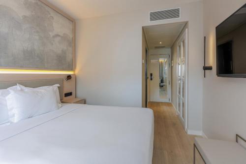 a bedroom with a white bed and a television at Hotel Vilamarí in Barcelona
