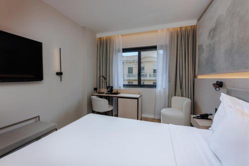 a hotel room with a white bed and a desk at Hotel Vilamarí in Barcelona