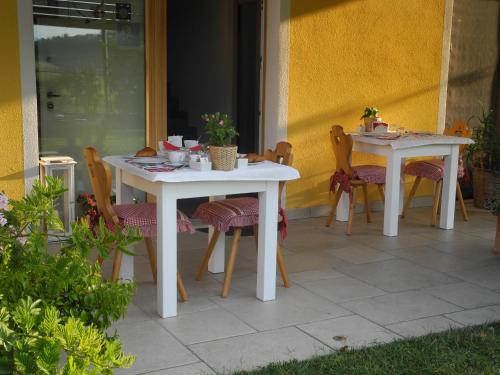 two white tables and chairs on a patio at B&B Mimosa e Lillà in Fumane