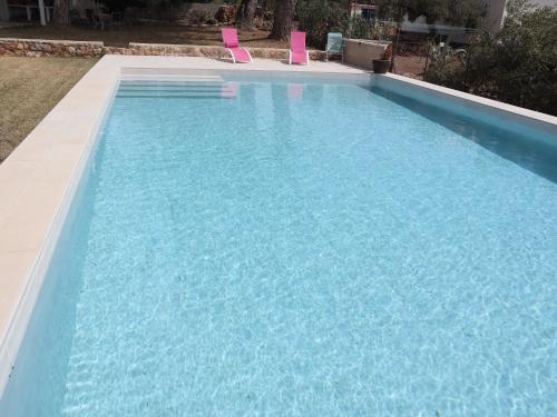 einen großen blauen Pool mit zwei rosa Stühlen in der Unterkunft Nina´s Paradise in L'Ampolla