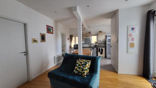 un salon avec un canapé bleu et une cuisine dans l'établissement Au Gré de L'ill 'Les Cigognes', à Horbourg-Wihr