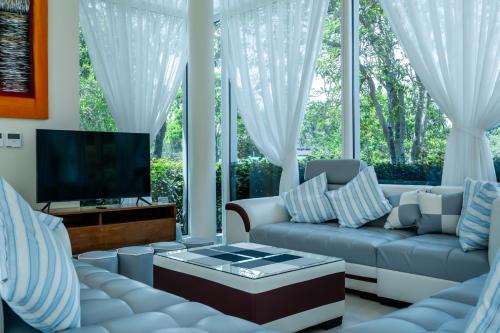 a living room with a couch and a tv at Sunshine Beach Villa Mai Khao in Mai Khao Beach