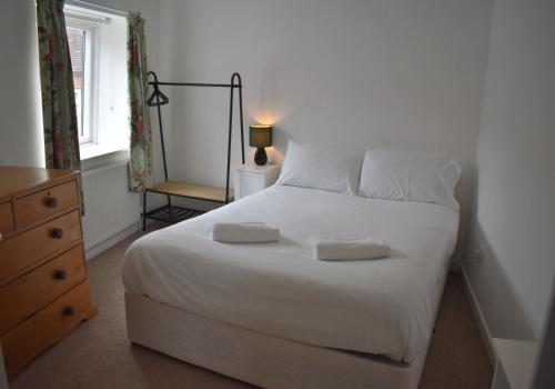 a bedroom with a white bed with two pillows on it at Chichester Retreat - Quiet City Centre Apartment in Chichester