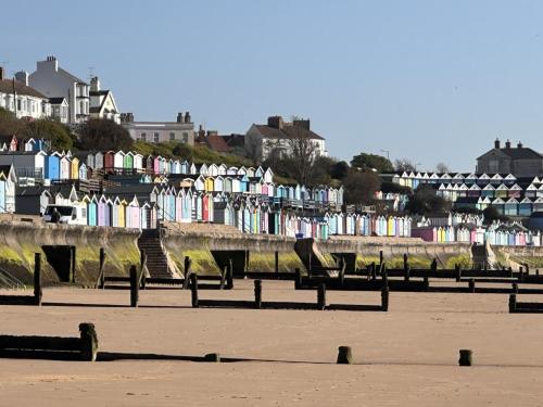 a row of benches on a beach with houses at High view house, 3 bed flat, Number 41A in Walton-on-the-Naze