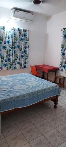 Cama en habitación con cortinas y mesa en RUKMINI Apartment, en Bangalore