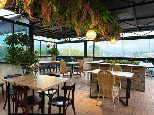 a restaurant with tables and chairs and windows at Hill Hotel in Kutaisi