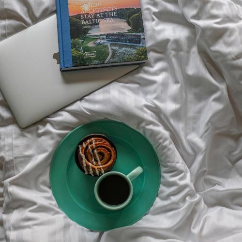 a book and a cup of coffee and a pastry on a bed at Villa Huno in Borre