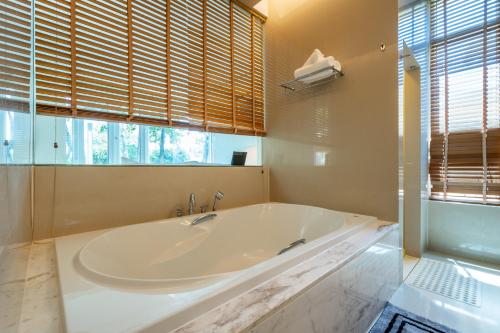 a large white tub in a bathroom with a window at Sunshine Beach Villa Mai Khao in Mai Khao Beach