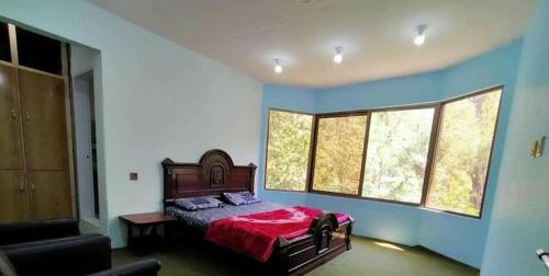 a bedroom with a bed with a red blanket at Ilyasin Guest House in Skardu
