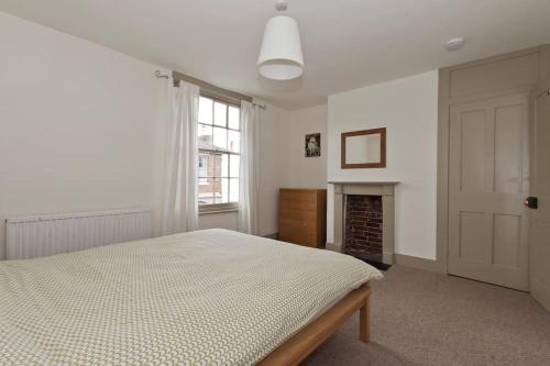 um quarto branco com uma cama e uma lareira em Gorgeous Georgian House em Canterbury