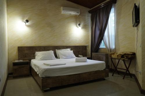 een slaapkamer met een bed met witte lakens en een raam bij Aquapark Hotel & Villas in Jerevan