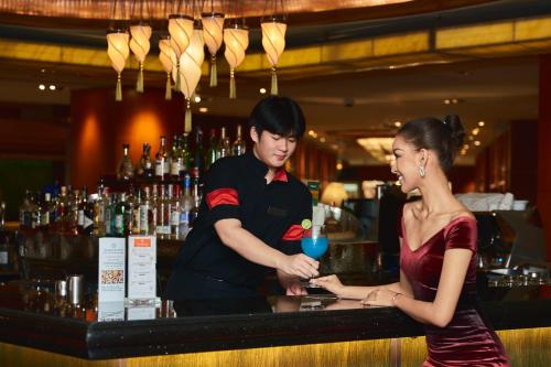 Ein Mann und eine Frau stehen an einer Bar in der Unterkunft Royal Orchid Sheraton Hotel and Towers in Bangkok