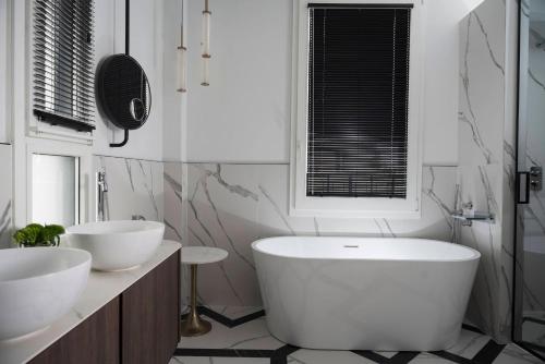 a white bathroom with two sinks and a tub at Hotel Maestrale in Riccione