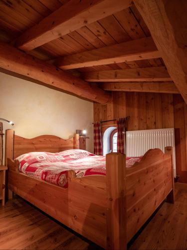 a large wooden bed in a room with wooden ceilings at Chalet Les Liouès in Sollières-Sardières